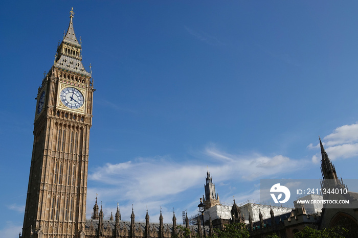 Elizabeth Tower, known as Big Ben, rising into a blue sky above the Houses of Parliament in Westminster, London, UK.