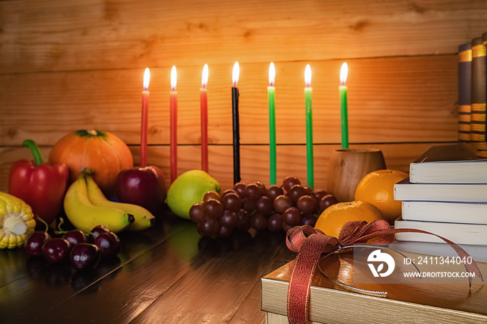 Kwanzaa holiday concept with decorate seven candles red, black and green, gift box, pumpkin,corn and fruit on wooden desk and background.