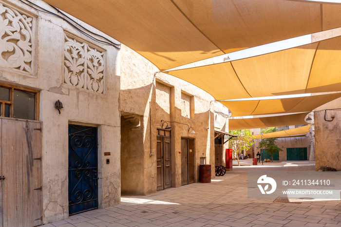 Al Fahidi Historical District stone street with traditional arabic style buildings with ornaments and sunshades above, Deira, Dubai, United Arab Emirates.