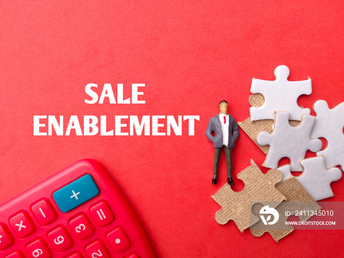 Calculator,miniture people and puzzle with text SALE ENABLEMENT on red background