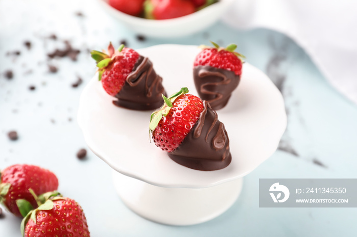 Dessert stand with delicious strawberries dipped in dark chocolate on color background