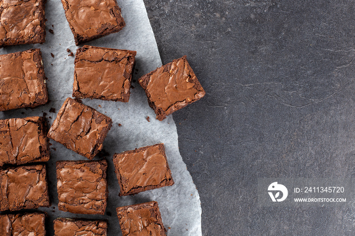 Chocolate brownie on paper on dark grey base top view flat lay