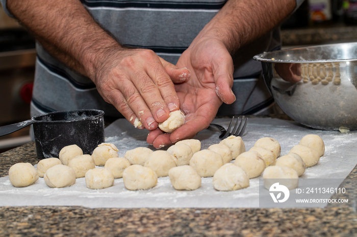 Man rolls out balls of gnocchi dough