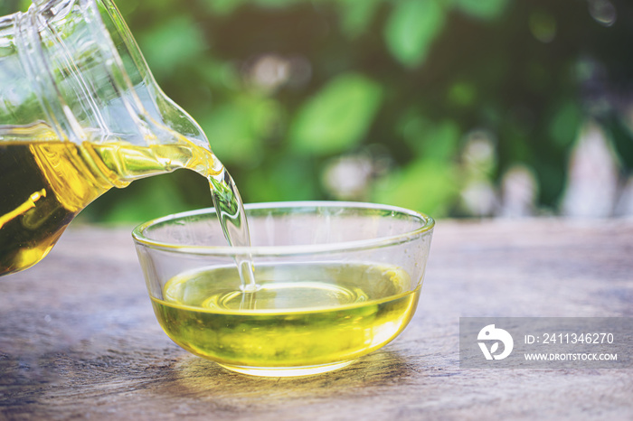 Bottle pouring virgin olive oil in a bowl close up