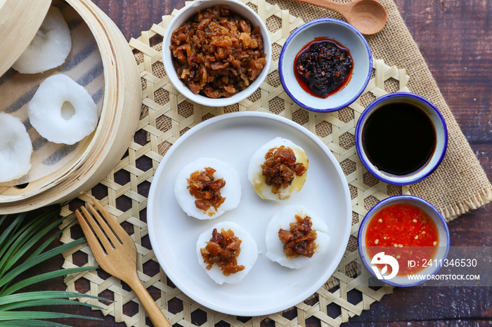 Steamed rice cake top with preserved turnip served with sweet soy sauce and chili sauce - In Chinese food called Chwee Kueh at top view on wood table