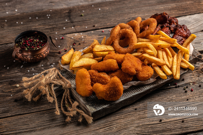 take away fast food products fried chicken with french fries and nuggets meal, junk food and unhealthy food on a wooden board. banner, menu, recipe place for text