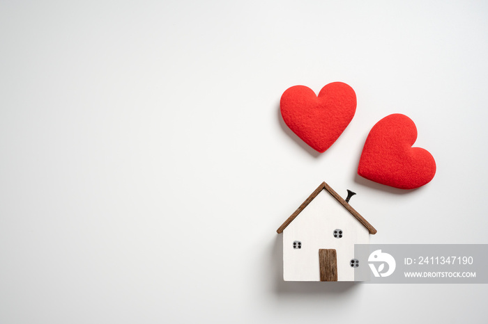 Small wooden house with hearts. Concept of protection or saving for buying new living area. Topic for loan and investment.