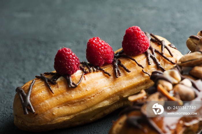 Eclairs with peanuts, chocolate icing and raspberries