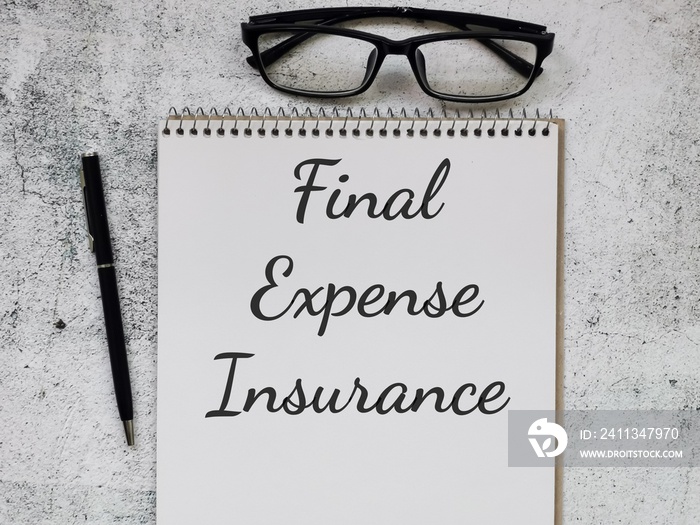 Phrase Final Expense Insurance written on note book with pen and eye glasses. Business concept.