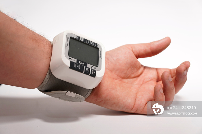 man’s hand with wrist blood pressure monitor on white background