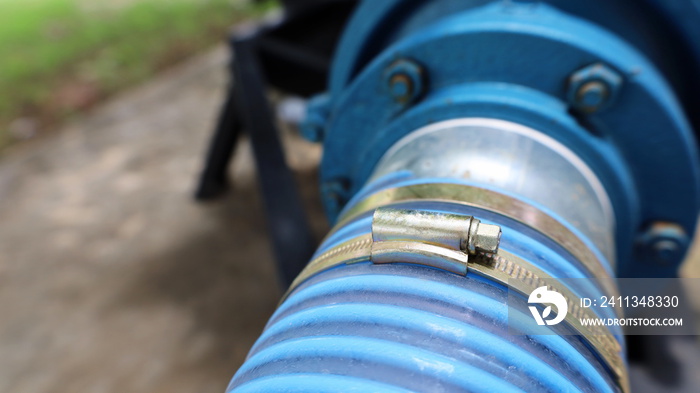 Close-up of the water pump hose clamp. The soft plastic hose is connected to the blue pumping pump with copy space. Selective focus