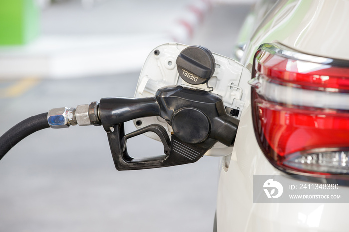 refilling the white car with diesel fuel at the refuel station. diesel fuel dispenser.