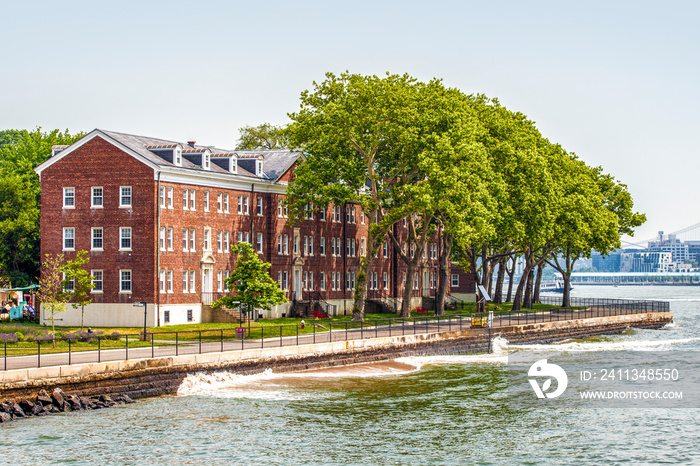 Governors Island and red old retro brick buildings near fort Jay separated from Brooklyn by Buttermilk Channel during sunny summer day in New York City, USA