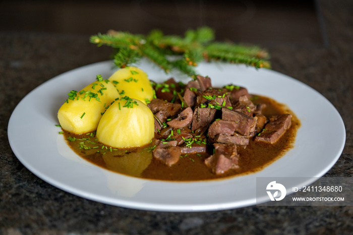 ready to eat - roasted heart, kidneys and liver from a red deer calf with potatoes, sauce and a spruce twig deko