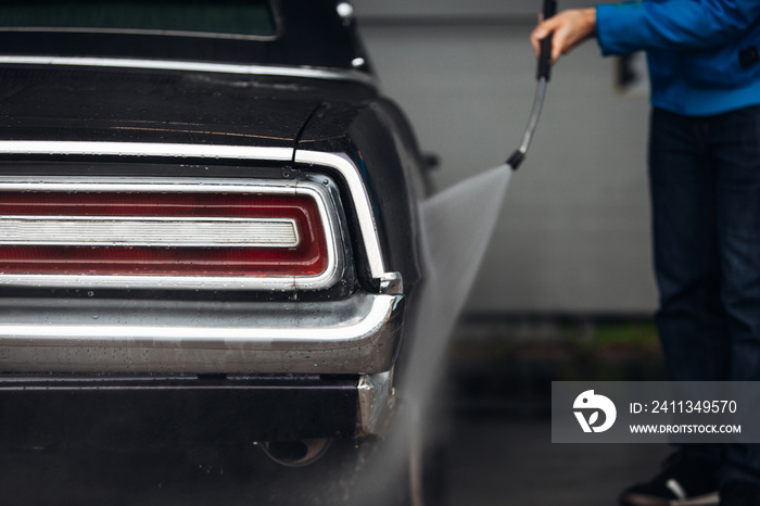 Man washing his classic car in a self-service car wash station