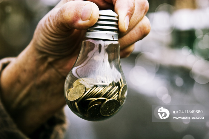 Coins in a glass lamp in old wrinkled hands closeup