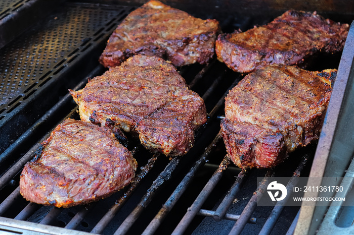 Closeup of BBQ steaks cooking on a grill