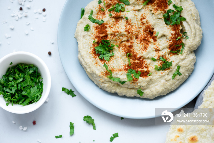 Eggplant dip baba ganoush (mutabbal) with herbs and paprika on gray wooden background. Selective focus. Traditional arabian food. Top view