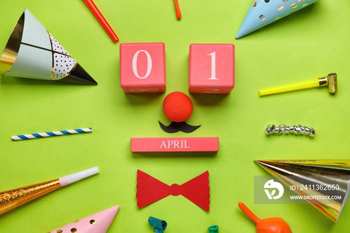 Cube calendar with date 1 APRIL and party decor for Fool’s Day celebration on green background