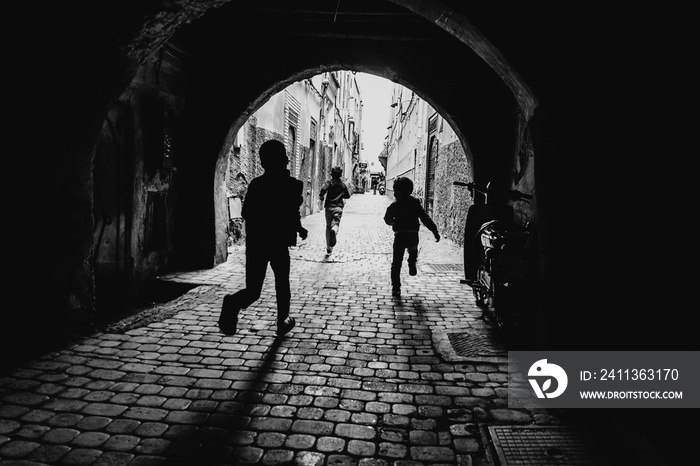 Silhouette of boys running through a tunnel in Marrakech, Morocco