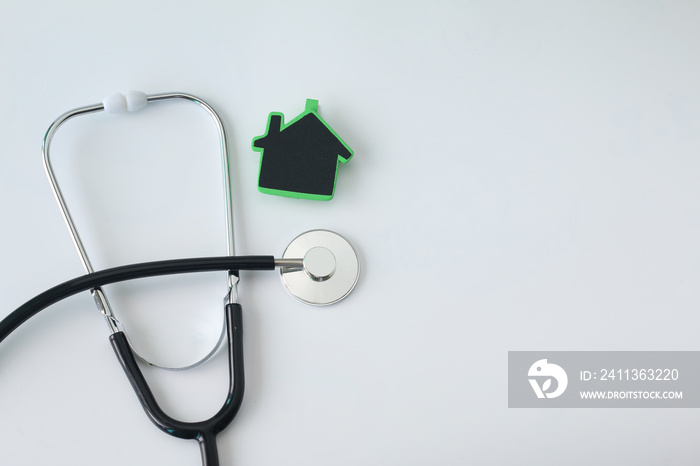 green home with stethoscope on white background