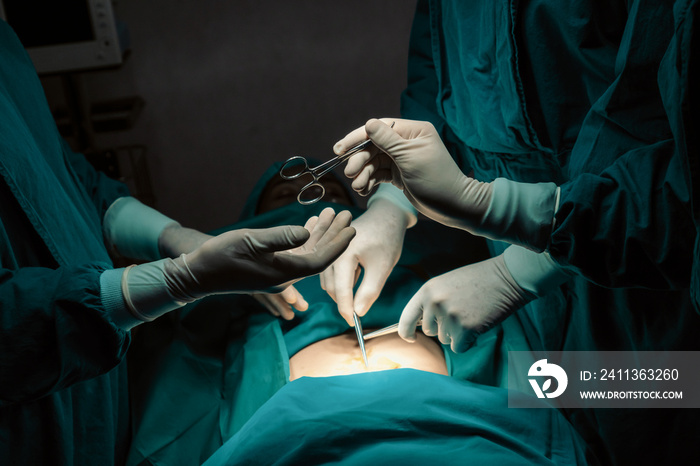 Image of surgical team perform surgery operation, nurse hand out sterile scissors to surgeon as supportive and cooperative in operation room concept.