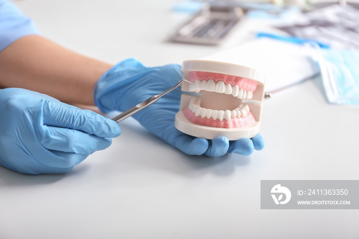 Dentist with artificial jaw and dental tool at light table