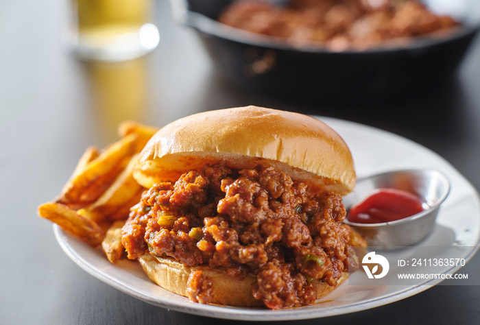 sloppy joe sandwich on plate with french fries and ketchup