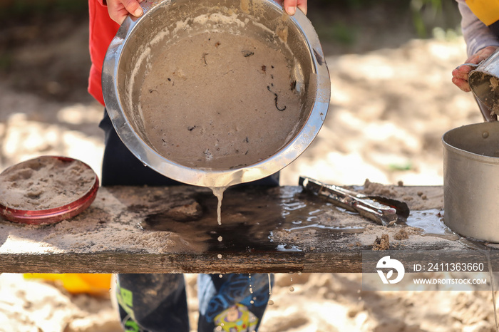 Preschool children playing in sandpit making mud pies at kindergarten