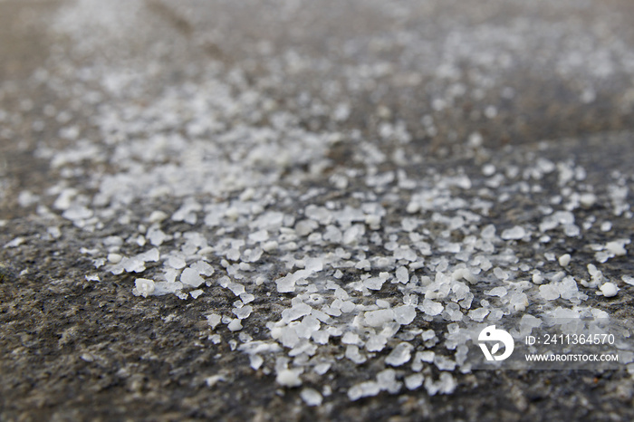 De-icing chemicals on the pavement. Pavement is sprinkled with technical salt or salt mixtures based on it, soft focus, copy space. Reagent - technical salt will make the road safe.