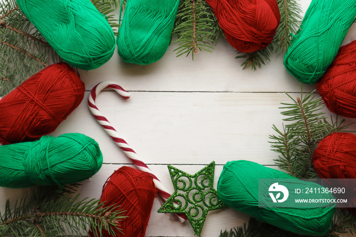 Fir tree branches and yarn threads on light wooden background. Christmas knitting concept