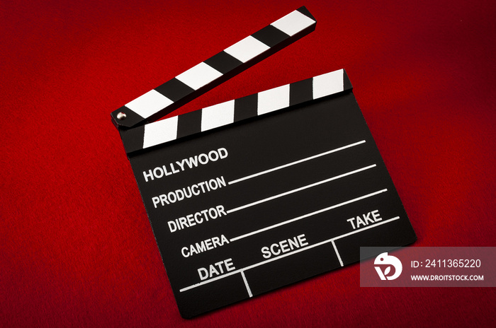 Hollywood and the movie industry concept with a vintage movie clapper board on red background