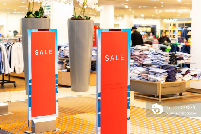 Red bright sale word banner on anti-thieft gate sensor at retail shopping mall entrance. Seasonal discount offer in store