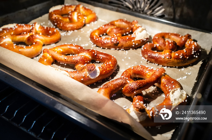 Appetizing, baked, soft pretzels with the addition of coarse salt lie on the tray in the oven. Traditional food. Oktoberfest.