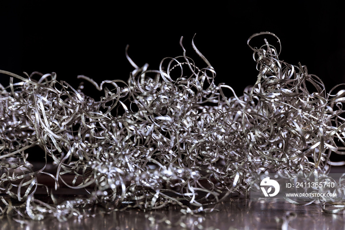 Shavings scrap metal. Curly metal shavings on a black background. Recyclable materials, scrap metal, steel waste.