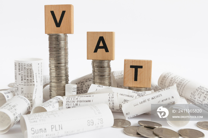 Rows of coin stacks with toy blocks among the receipts  symbolizing value added tax