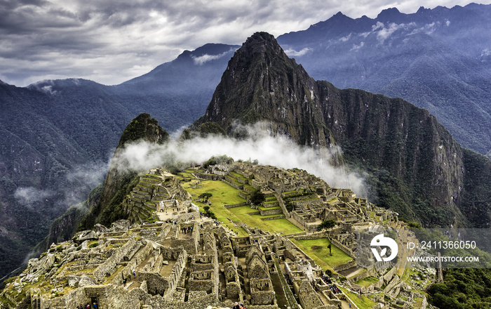 Ruins of Machu Picchu and Huayna Picchu covered by mystical cloud. Panoramic summer view from above.