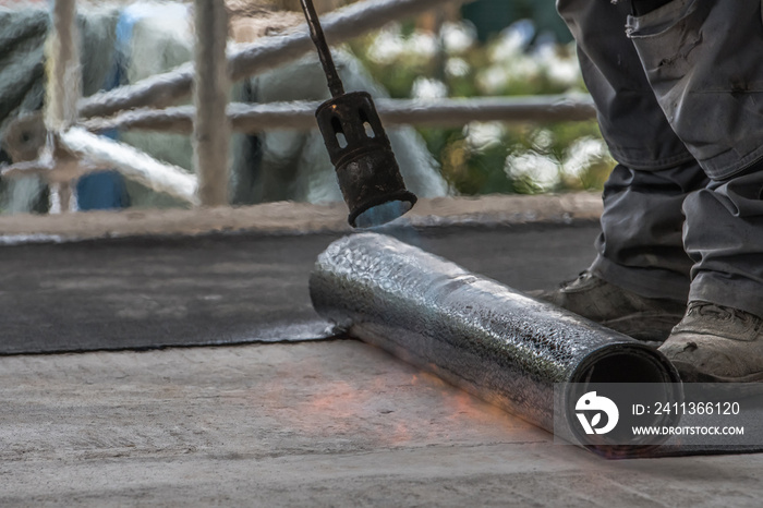 Professional installation of the waterproofing on the concrete foundation. Installation with rolls of bituminous sealing membrane by heating and melting of bitumen rolls by torch to flame while sealin