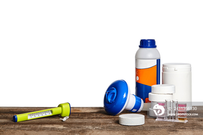 Equipment with chemical cleaning products and tools for the maintenance of the swimming pool on a wooden surface against white background.