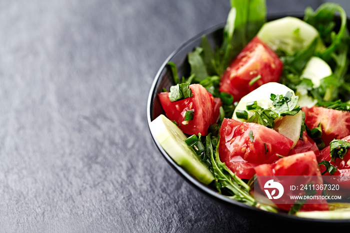 Salad with Tomatoes, Cucumber and Rocket on stone Background. Healthy Snack Idea. Close up. Copy space.