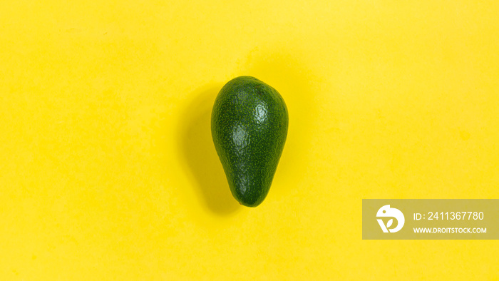 Green ripe avocado on a yellow background close-up.