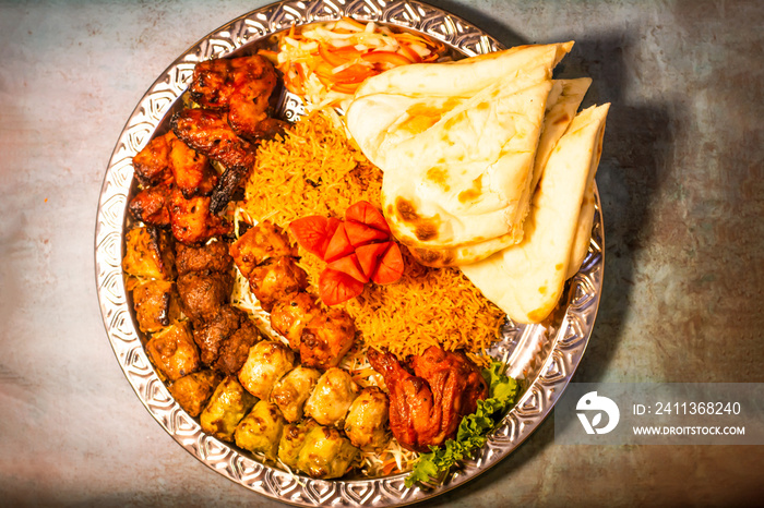 tikka boti seekh kabab platter with pulao, roti, lime and salad in a dish top view of middle eastern barbeque dish