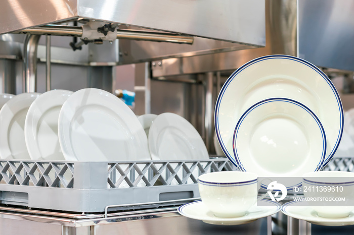 Plate cup set and many white plate on basket in automatic dishwasher machine for cleaning in kitchen room restaurant