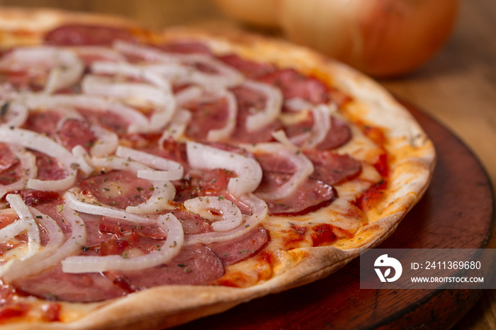 pepperoni pizza on wooden background. Brazilian pizza called pizza de calabresa.