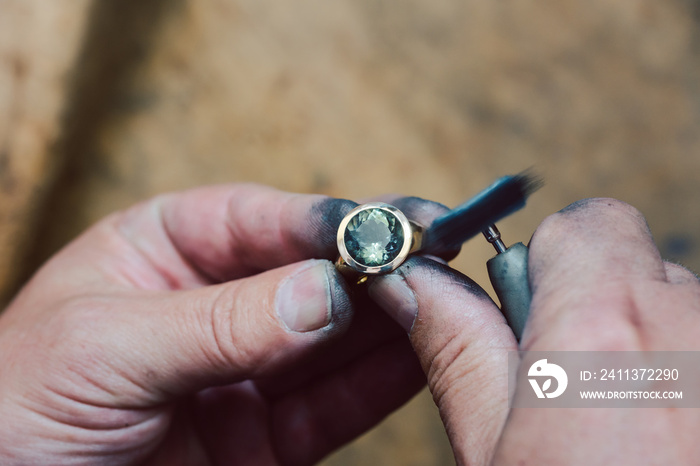 Closeup on hands of goldsmith working on a ring in his workshop