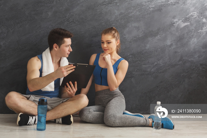 Young couple discussing workout plan at gym