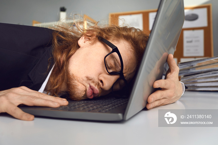 Funny employee, technofile or nerdy student in glasses enjoys working on his computer. Happy office worker who loves his job sitting at desk and tenderly hugging and kissing his laptop