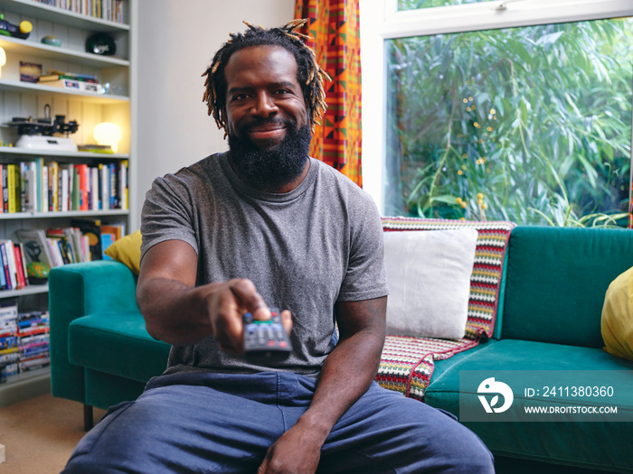 Man sitting on sofa, holding remote control