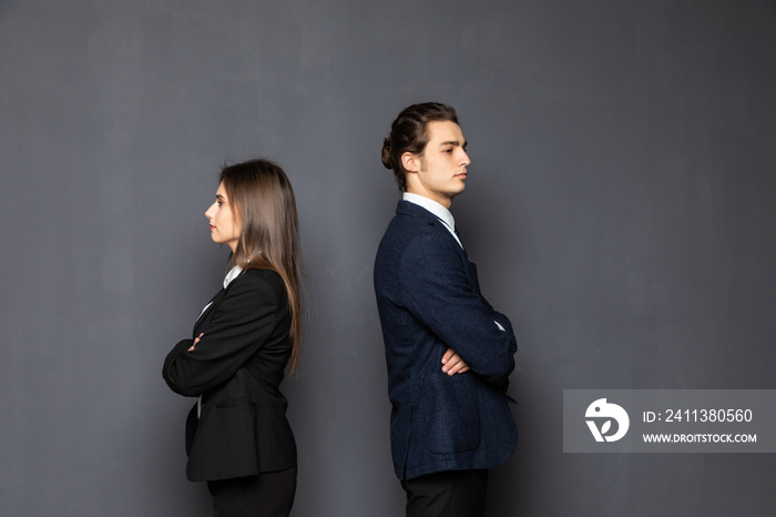 Business man and woman standing back to back isolated on gray background. Teamwork concept