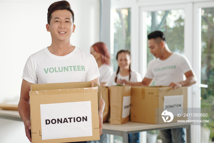 Positive handsome young man enjoying working at community donation center